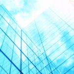 view of a contemporary glass skyscraper reflecting the blue sky